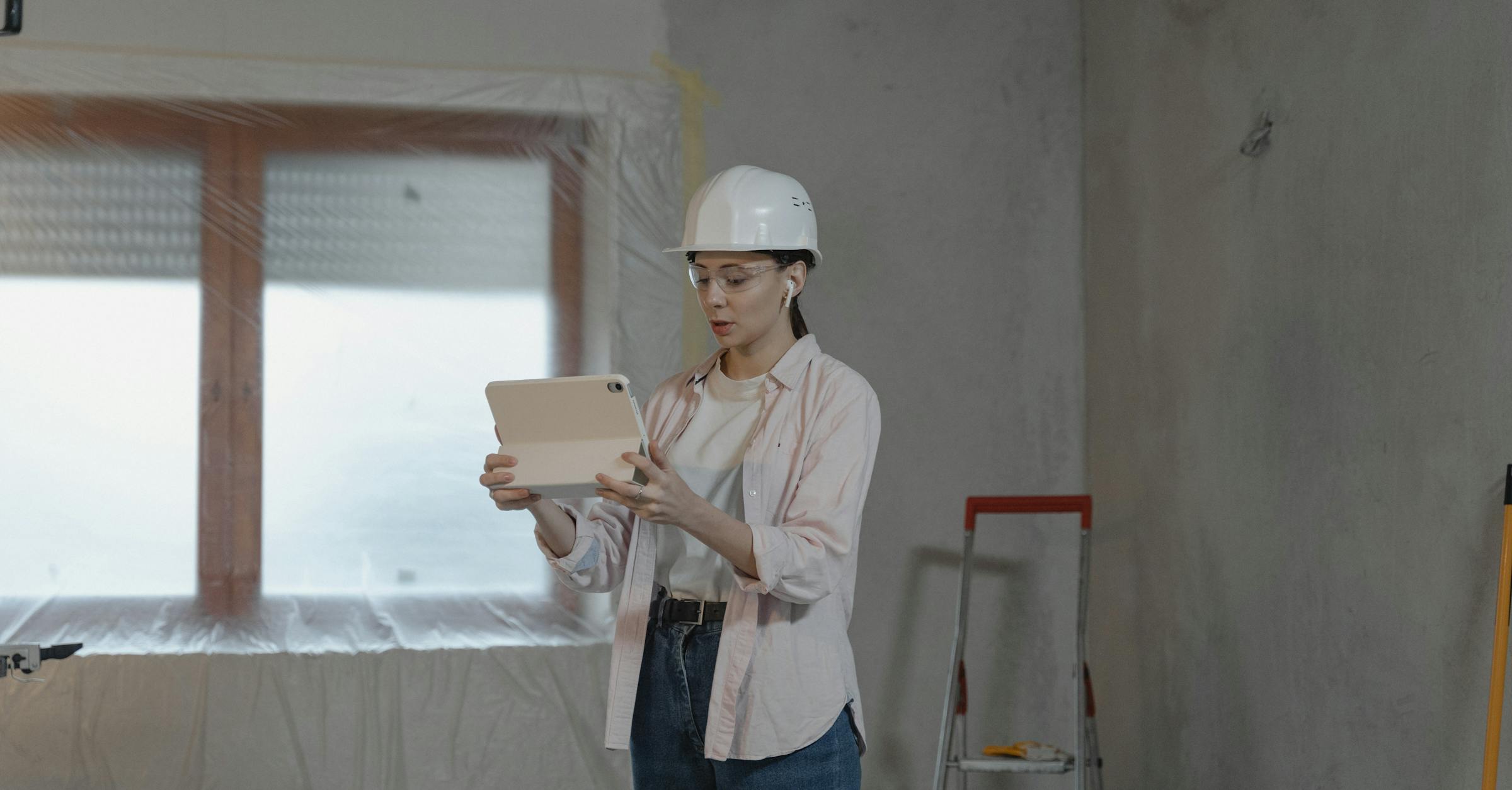 Construction professional using a tablet inside an unfinished house for AI takeoff review