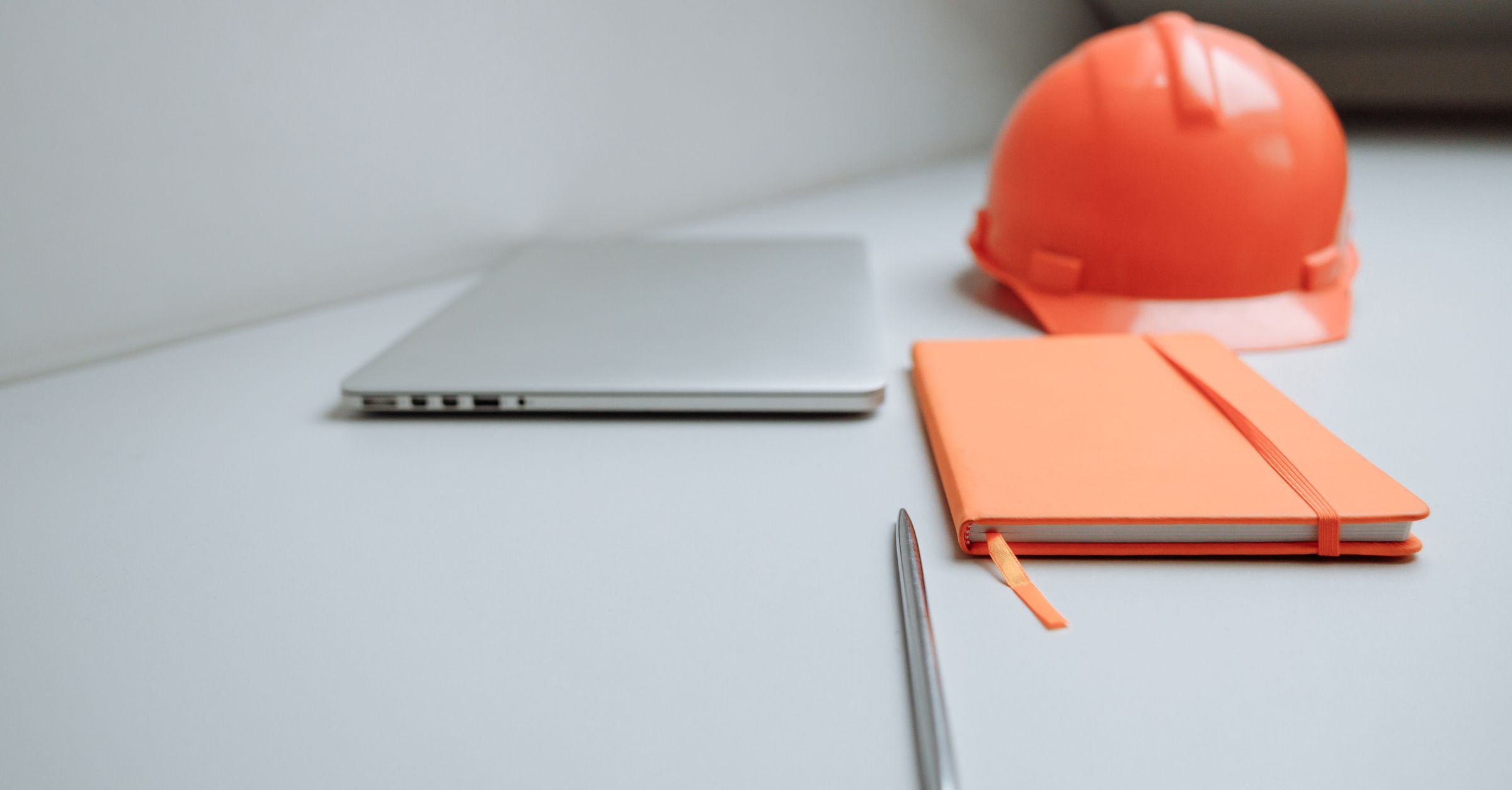 Construction notebook, laptop and safety helmet for daily jobsite logs