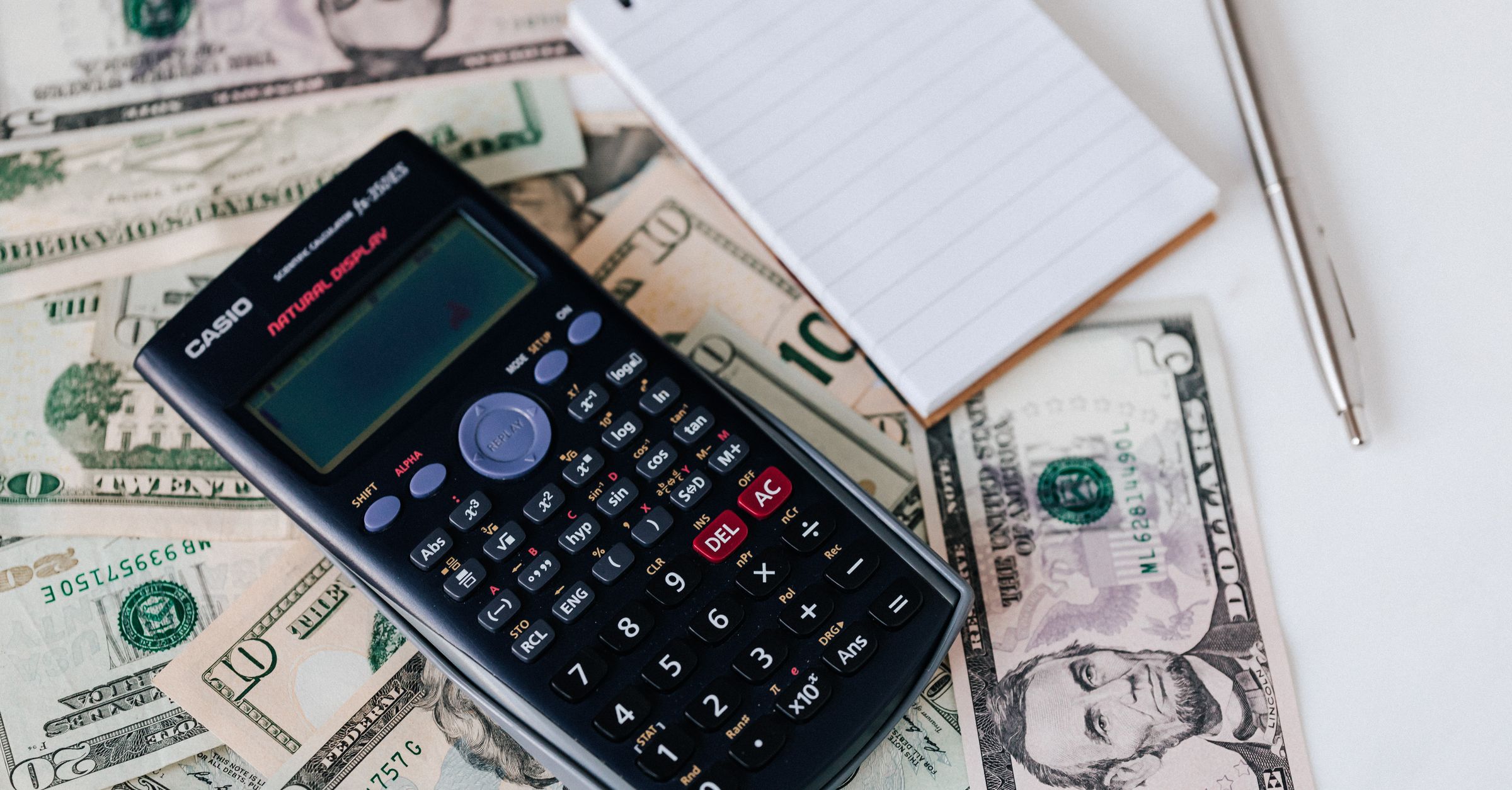 Calculator and notepad on money for construction job costing and budget tracking