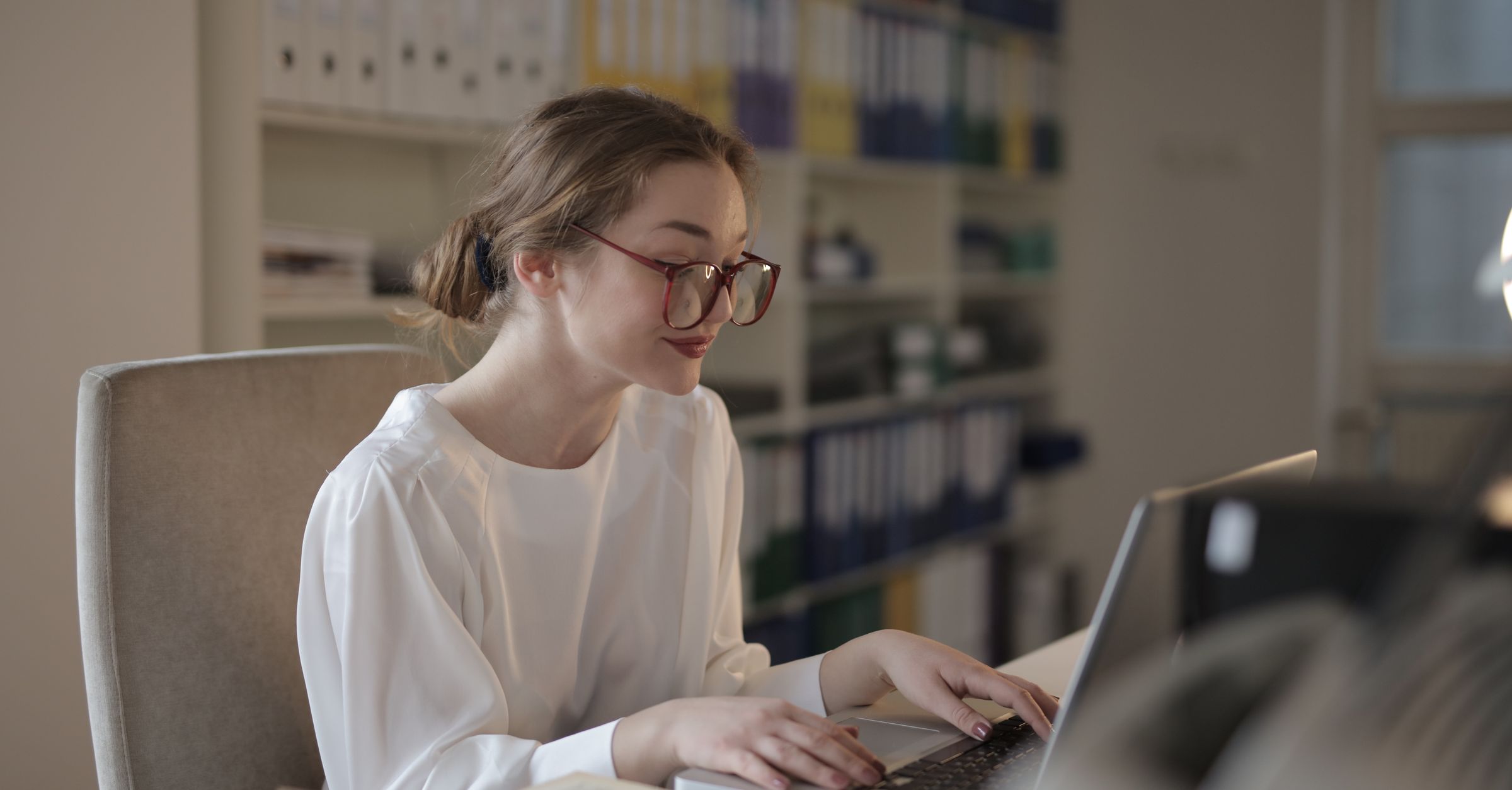 Vertriebsmitarbeiterin arbeitet am Laptop mit einem KI-Vertriebsassistenten im Büro